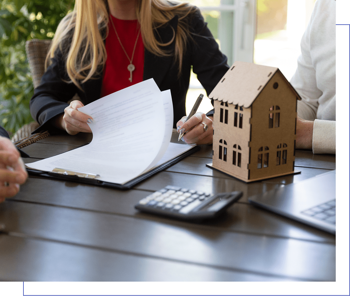 People sitting at a table reviewing documents with a small house model and a calculator nearby.