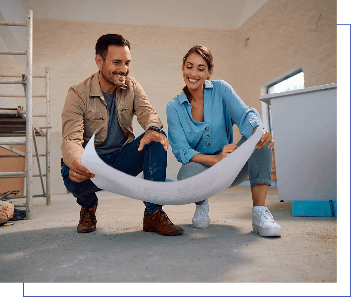 Two people reviewing architectural plans in a room with scaffolding and construction materials.